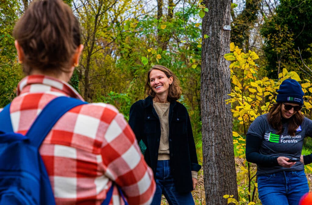 Deputy Director of Development, Kate Sease, stands in a group of volunteers, with foliage in background