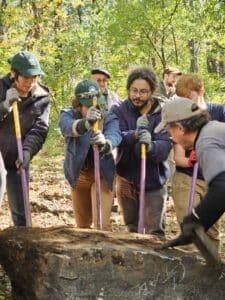 Group of trail maintainers lift large boulder with hoes