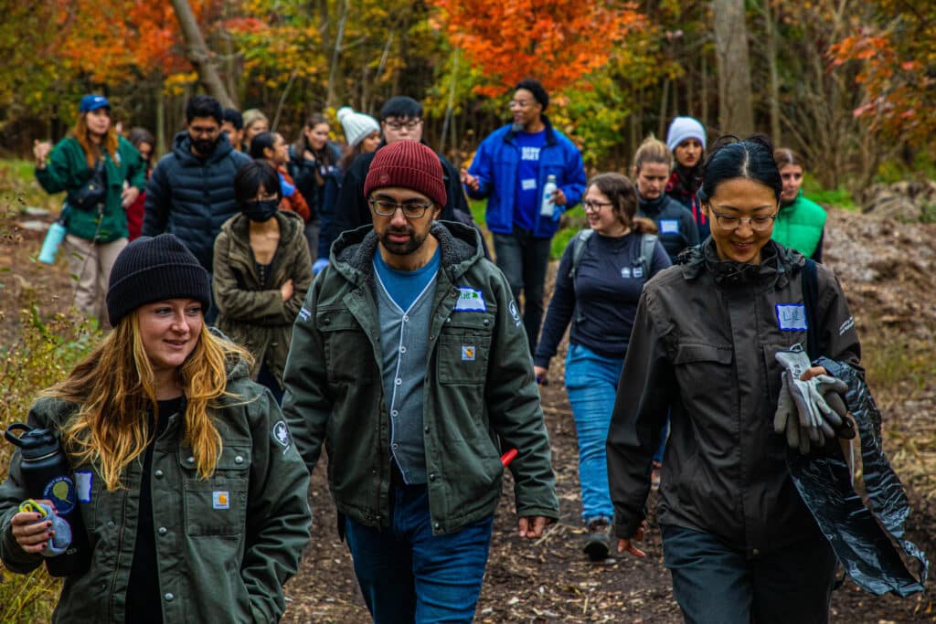 A group of NYC Parks and NAC employees walk on a trail in autumn