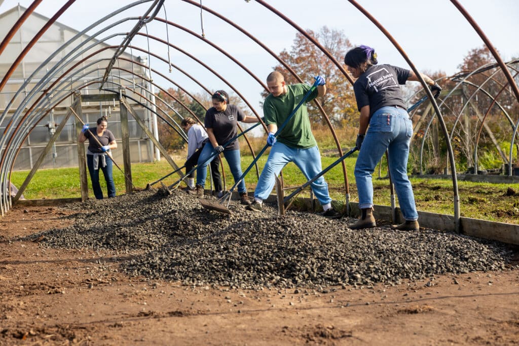 A group of interns and staff shovel gravel at the Greenbelt Native Plant Center
