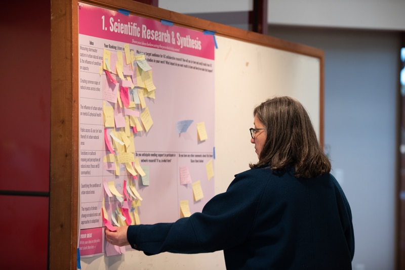 Helen Forgione, NAC senior ecologist, adds a sticky note to a bulletin board that reads “scientific research and synthesis”