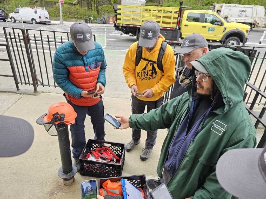 A group of trail maintainers surround Josh Otero who has his phone pointed outward