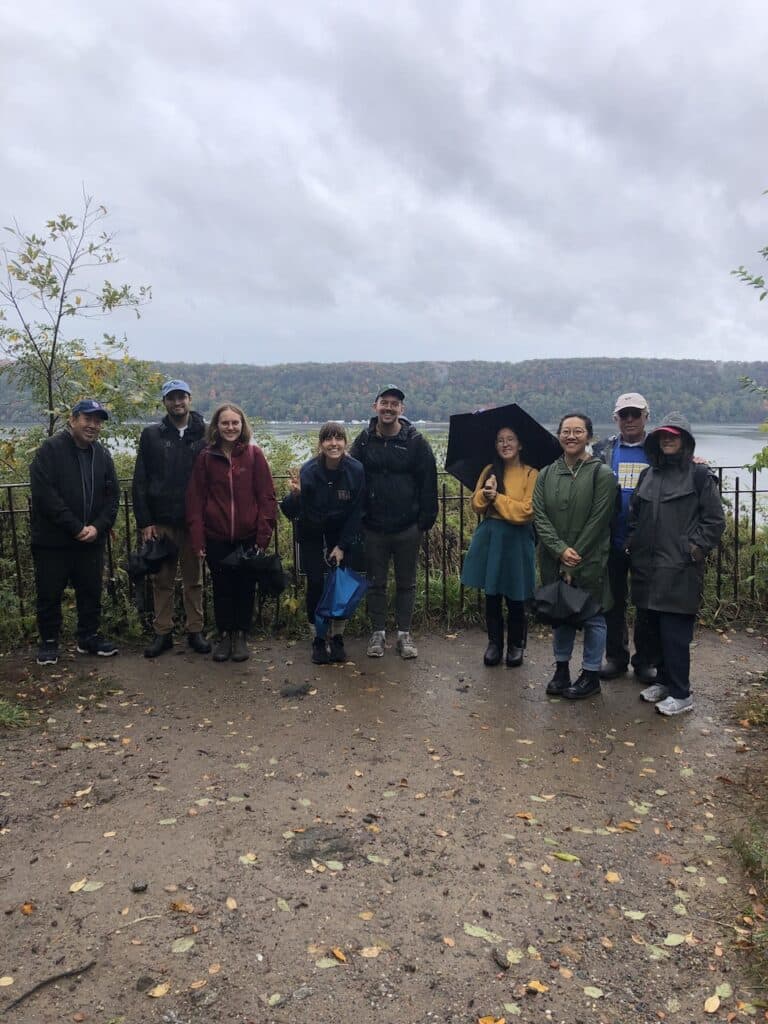 A tour group poses in front of the Hudson river in Inwood Hill Park on a cloudy day
