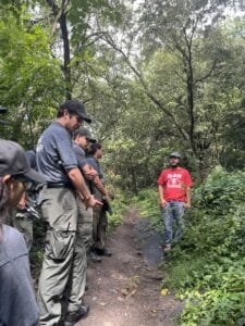 Man in red shirt speaks to urban rangers on a forest trail