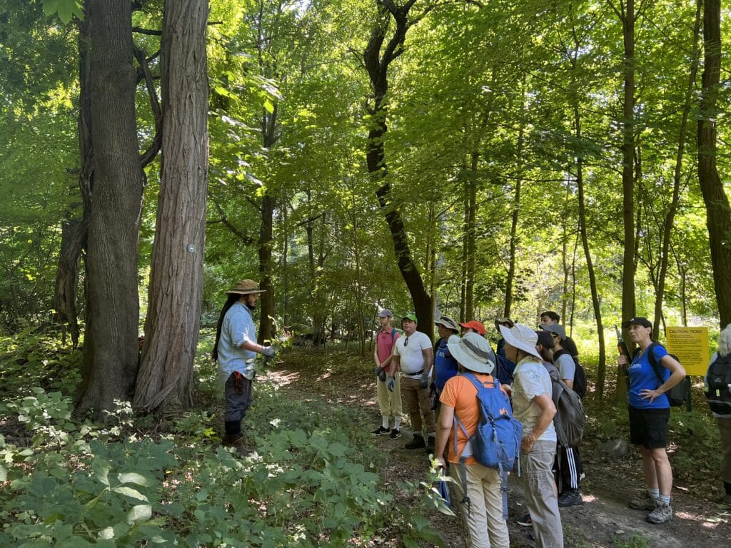 man speaking to a crowd in a forest trail