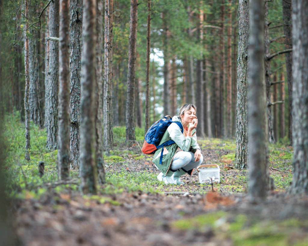 woman smells plant in forest
