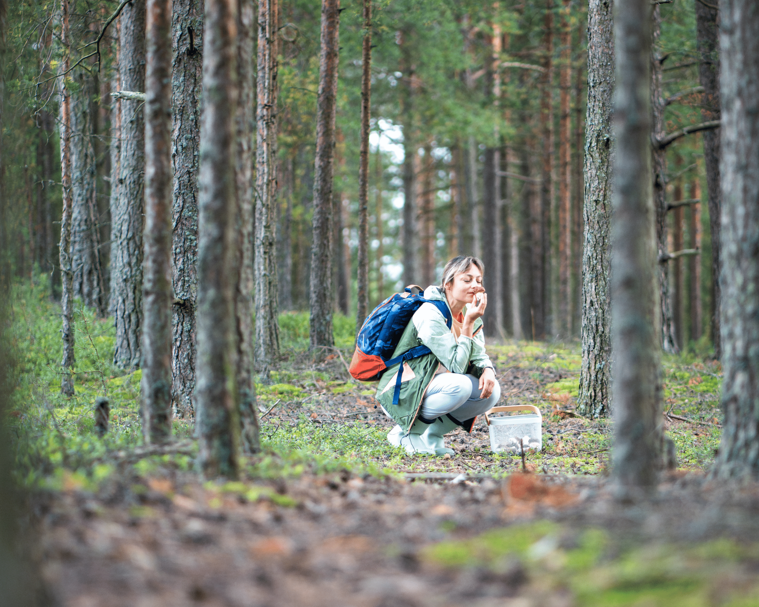 woman smells plant in forest